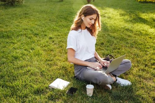 Photo of european woman 20s sitting on green grass in park with