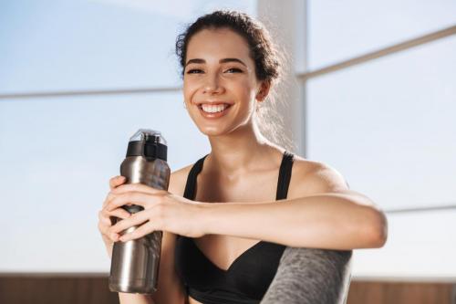 Smiling young sportswoman holding water bottle