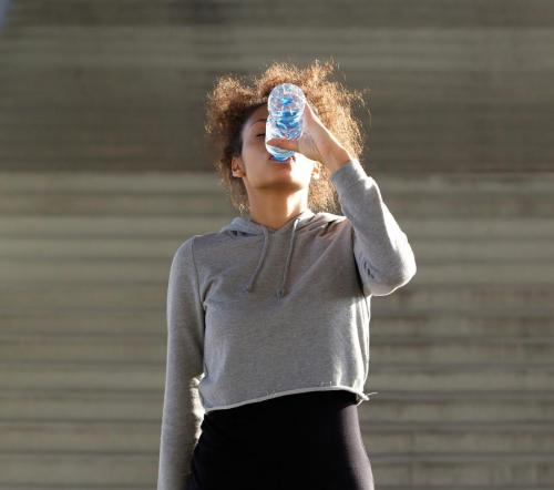 Thirsty young woman drinking from water bottle